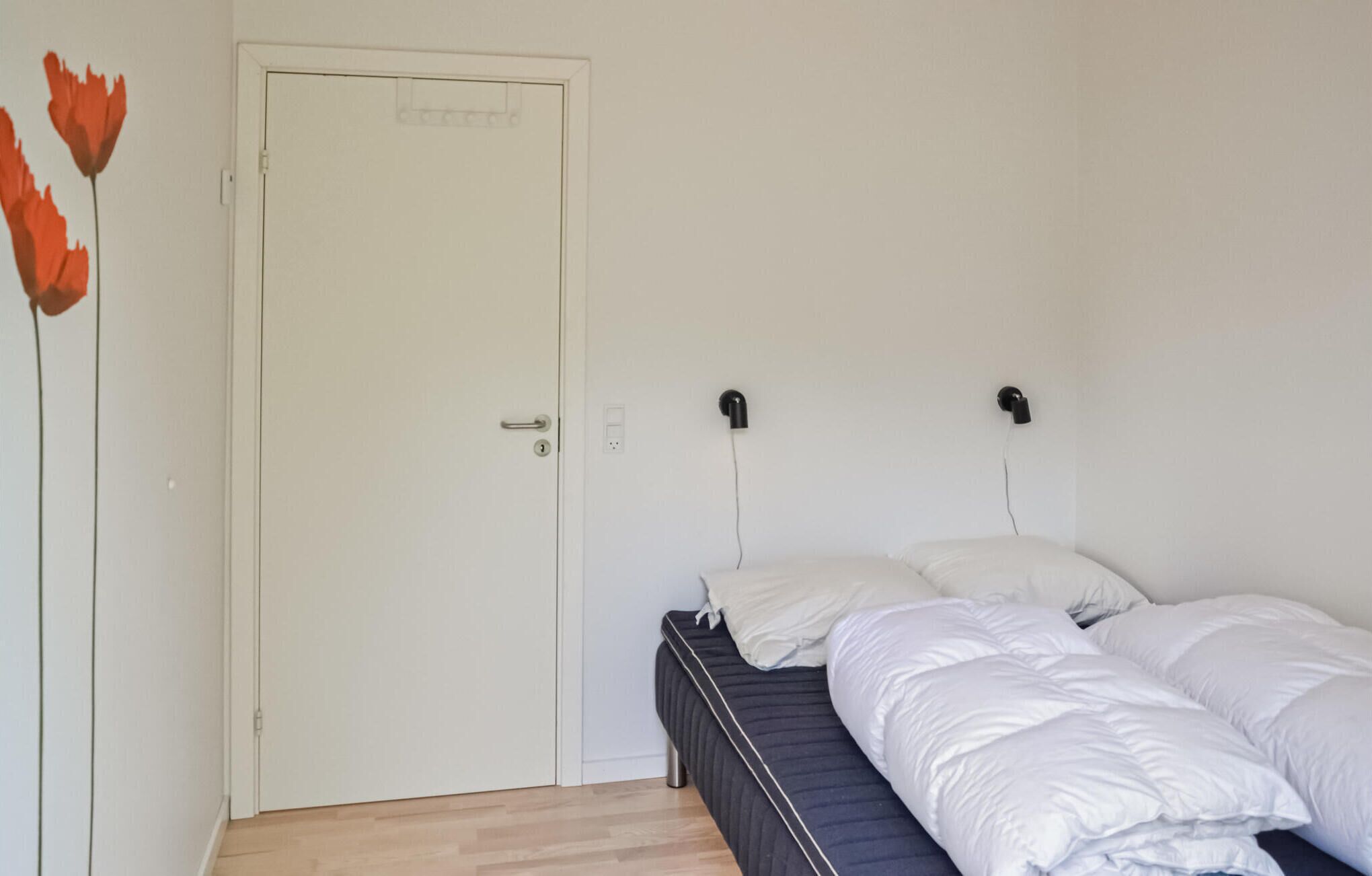 Een slaapkamer met een bed, een deur en een wandlamp.