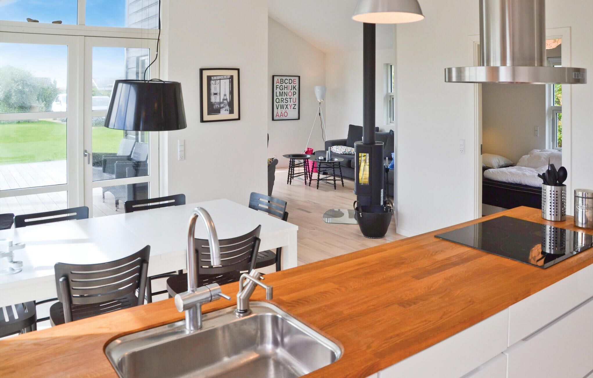 Une cuisine moderne dotée d’un plan de travail en bois, d’un évier en acier inoxydable et d’un coin repas avec une table et des chaises.