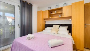 A bedroom with a bed, a sliding glass door, and wooden cabinets above the bed. - Studio with balcony and air conditioning (Malinska)