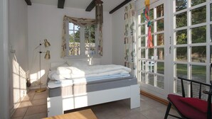 A bedroom with a bed, a bedside table, a lamp, a window with curtains, and a view of the outdoors. - 3 bedroom awesome home in Skælskør (Skælskør)