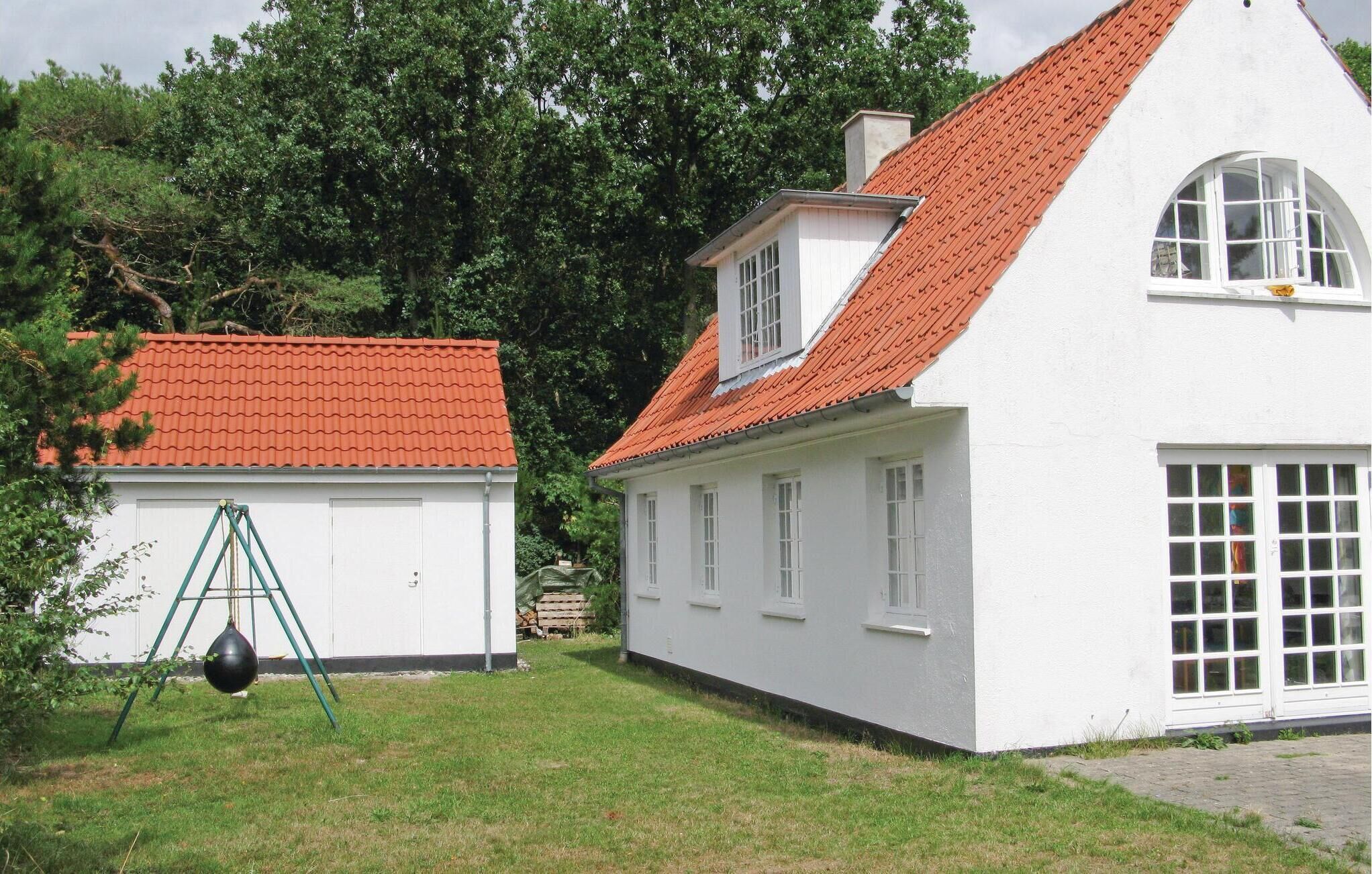 A white building with a red-tiled roof, a large window, and a door.