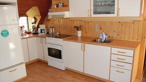 A compact kitchen with white cabinets, a built-in oven, a coffee maker, and a sink.