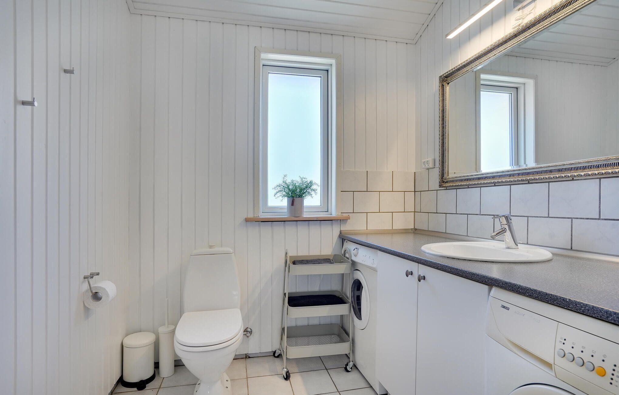 A modern bathroom with a toilet, sink, and washing machine.
