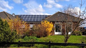 A house with solar panels on the roof, surrounded by autumn foliage and a brick pathway. - Vacation cottage Seestern, Germany (Friedrichskoog)