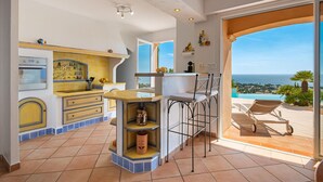 Una cocina con vista al mar, una zona de bar y un comedor con vistas.