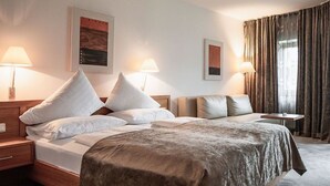 Hotellihuone, jossa on suuri sänky, kaksi yöpöytää, lamput ja näkymä ulos.