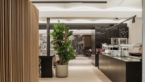 Una cocina moderna con una isla central, una planta en maceta y un menú en una pizarra.