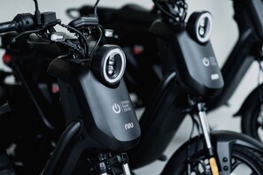 A close-up of electric scooters with a prominent power button and brand logo.