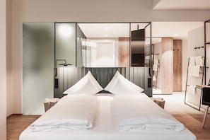 A modern hotel room with a large bed, a mirror, a wooden wardrobe, and a bathroom visible through a glass partition. - Double Classic - Hotel Goldenes Schiff (Bad Ischl)