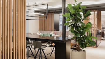 A modern dining area with a black table, chairs, and a potted plant.