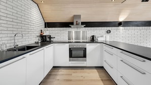 Ett modernt kök med vita skåp, en rostfri köksfläkt och en ugn från Bosch.