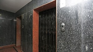 A hallway with a black and red tiled wall, a metal gate, and a door with a handle. - Hotel Ashoka Residency (Patna)