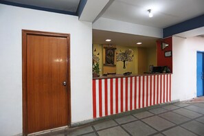 A reception area with a wooden door, a red and white striped counter, and a wall with a Buddha statue and decorative elements. - Hotel Ashoka Residency (Patna)
