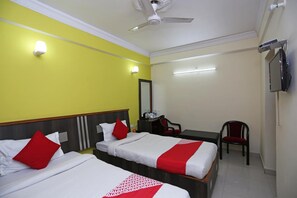A hotel room with two beds, a desk, a chair, a TV, and a ceiling fan. - Hotel Ashoka Residency (Patna)