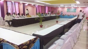 A conference room with a long table, chairs, and a stage. - Hotel Ashoka Residency (Patna)