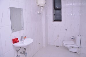 A bathroom with a white sink, a toilet, and a mirror. - Hotel Ashoka Residency (Patna)