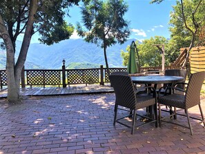 An outdoor patio with a table and chairs, a wooden fence, and a view of mountains.