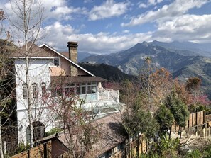 A house with a stone chimney, a balcony, and a view of mountains. - Aurora Villa (Ren'ai)