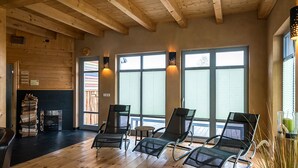 A room with wooden floors, a fireplace, and three lounge chairs.