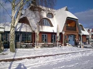 A snow-covered building with a unique architectural design, featuring large windows and a balcony. - 1-room apartment - holiday park in Plau (Plau am See)