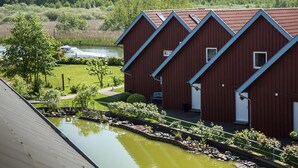 A row of red buildings with a pond in front.