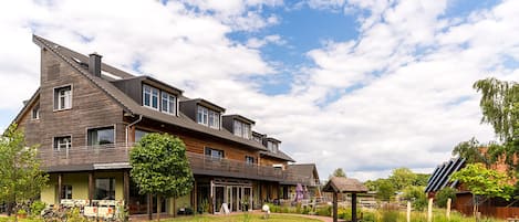 Een tweelaags huis met een ruime veranda, een metselwerkgardijn en een houten terras.