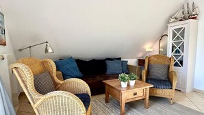 A cozy living room with wicker furniture, a dark sofa, a wooden coffee table, and a decorative cabinet. - (177) 2-room apartment Ostseeallee - apartment house dune castle (Kühlungsborn)