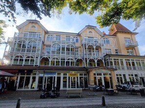 A multi-story building with balconies and storefronts, including a visible restaurant. - (177) 2-room apartment Ostseeallee - apartment house dune castle (Kühlungsborn)