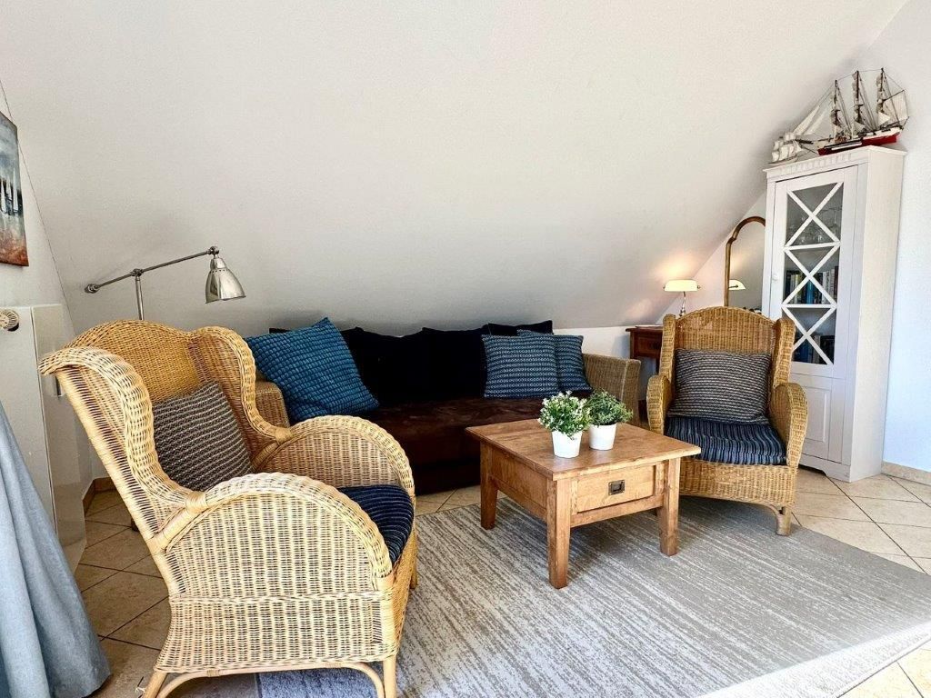 Un soggiorno accogliente con mobili in vimini, un divano scuro, un tavolino in legno e un mobile decorativo.