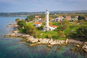 A coastal area with a lighthouse, buildings, and clear waters.