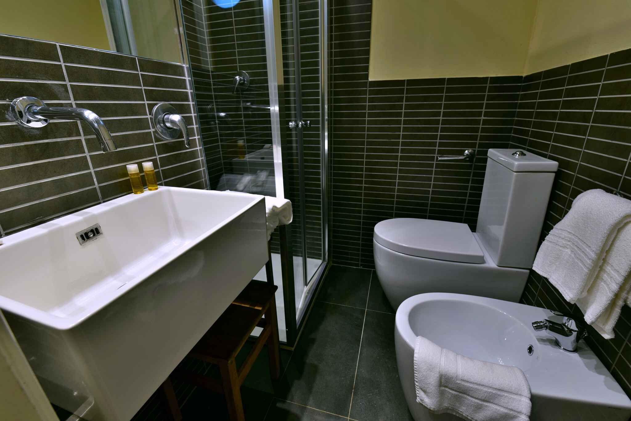 A modern bathroom with a large white sink, a toilet, and a shower area.