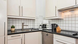 Eine moderne Küche mit weißen Schränken, einer schwarzen Arbeitsplatte, einer Kaffeemaschine, einer Mikrowelle und einem Geschirrspüler.
