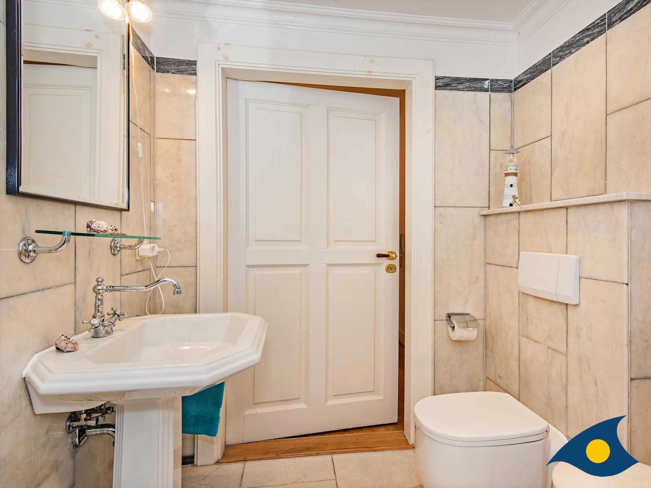 Une salle de bain avec un lavabo blanc, des toilettes et une porte.
