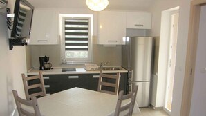 Eine moderne Küche mit Esstisch, Stühlen, einem Kühlschrank und einer Kaffeemaschine.