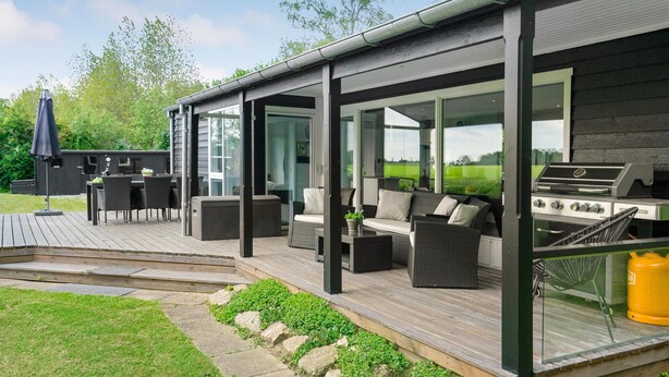 A covered outdoor patio with a grill, seating area, and a view of the surrounding landscape. - Amazing home in Bogense with WiFi (Bogense)
