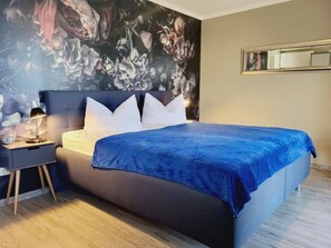 A bedroom with a bed, nightstand, and a floral wall mural.