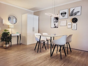 Un espace repas moderne avec une table blanche, quatre chaises et un luminaire suspendu.