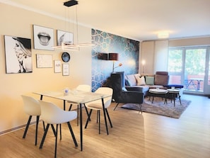 Un salon moderne avec un coin repas, comprenant un canapé, des fauteuils, une table basse et des œuvres d’art accrochées aux murs.