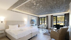 Ein modernes Hotelzimmer mit einem großen Bett, einem Schreibtisch, einem Stuhl und Blick ins Freie.