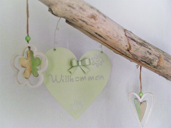 A branch with three heart-shaped decorations: one with a bow, one with a clover, and one plain.