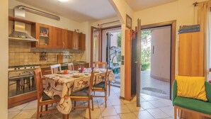 Cozinha compacta com armários de madeira, fogão a gás e área de refeições com mesa posta para quatro.