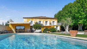 A yellow building with a swimming pool in front.