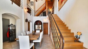 A spacious dining area with a wooden staircase leading to an upper level.