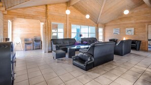A spacious room with a high ceiling and wooden walls, featuring a seating area with leather sofas and a glass coffee table. - Cozy home in Spøttrup with sauna (Spøttrup)