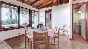 A dining area with a table set for four, wooden chairs, and a view of the outdoors through large windows. - Beautiful home in Belvedere di Aquileia with WiFi (Belvedere di Aquileia)