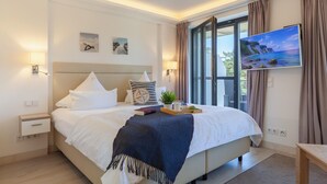 A modern hotel room with a large bed, a TV, and a window with curtains. - Lovely apartment in Binz with WiFi (Prora/Rügen)