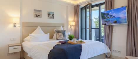 Ein modernes Hotelzimmer mit einem großen Bett, einem Fernseher und einem Fenster mit Vorhängen.