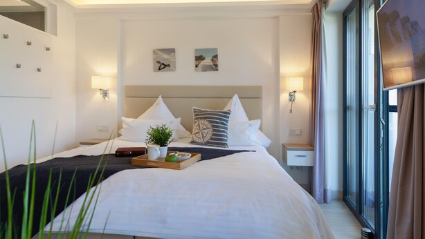 A hotel room with a bed, bedside tables, a window, and artwork on the wall. - Lovely apartment in Binz with WiFi (Prora/Rügen)