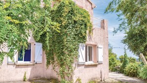 Un bâtiment rustique doté de deux fenêtres, l’une avec un volet bleu et l’autre avec un volet blanc.