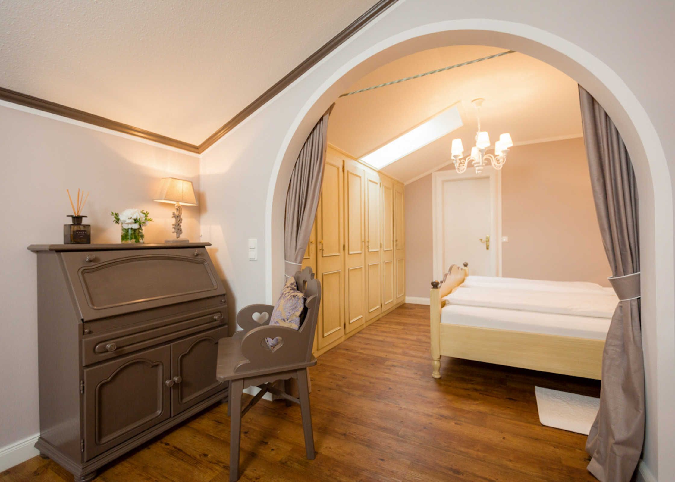 A bedroom with a bed, a dresser, a chair, and a wardrobe.